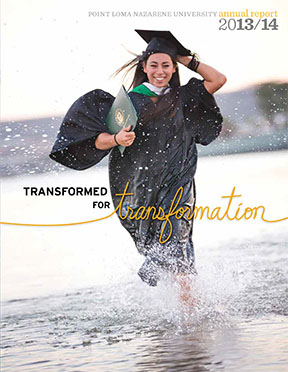 A young woman running in the shallows of the ocean in a cap and gown and holding a diploma.