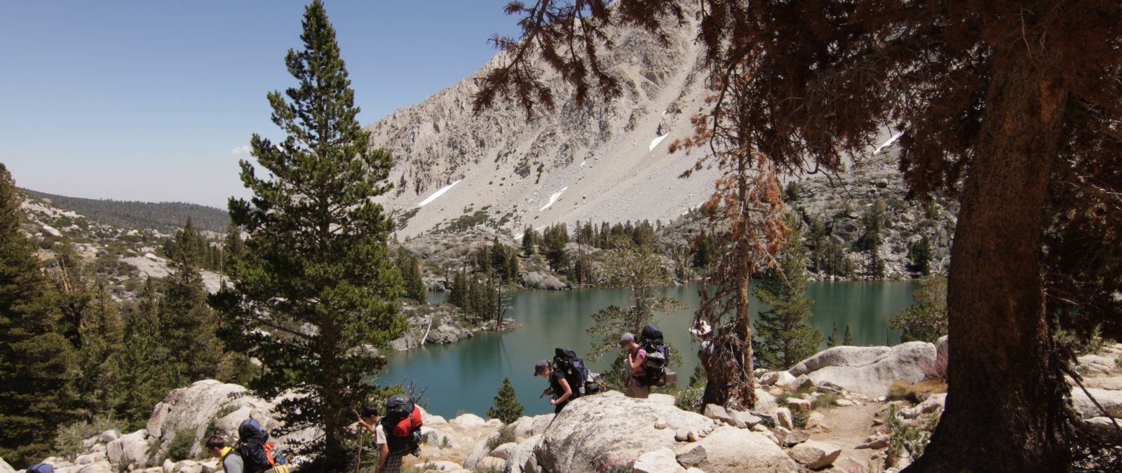 Students hike next to a lake