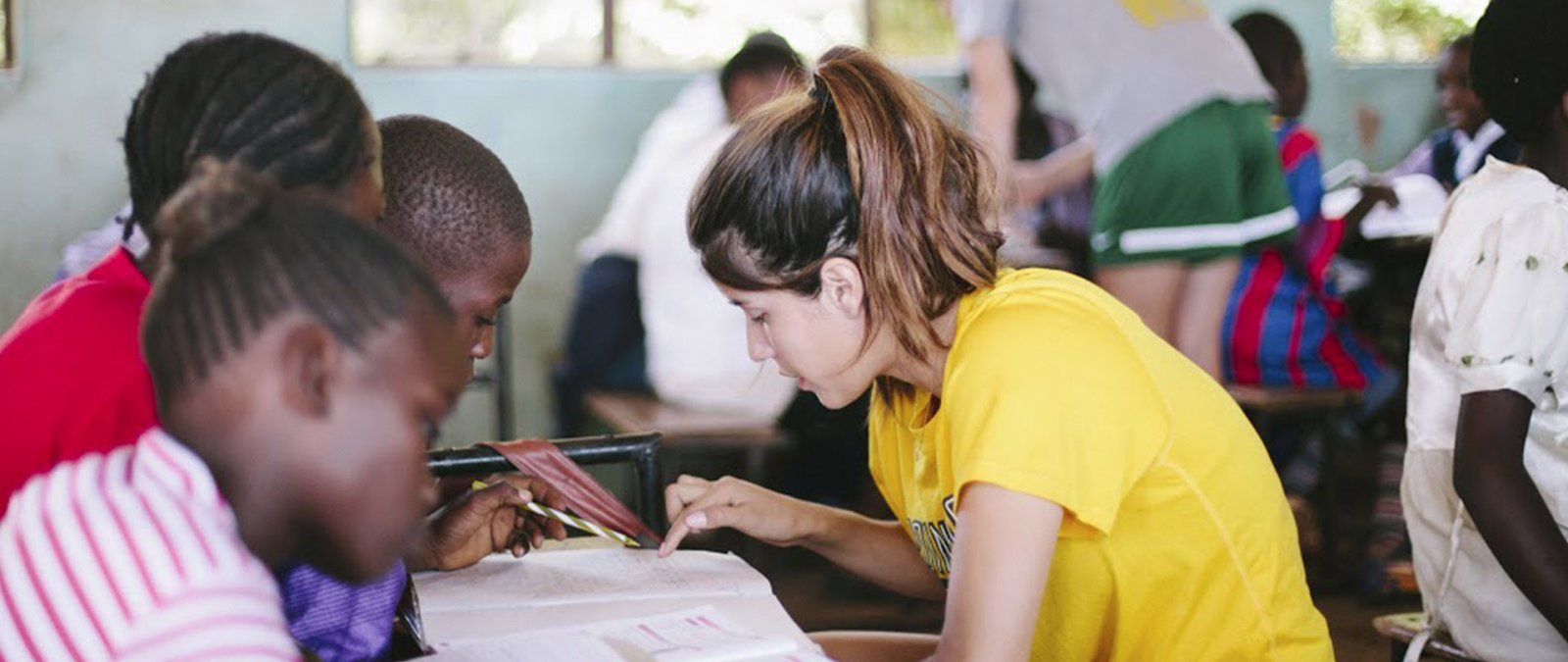 A PLNU student works with a student on homework while on a Loveworks trip to Zambia