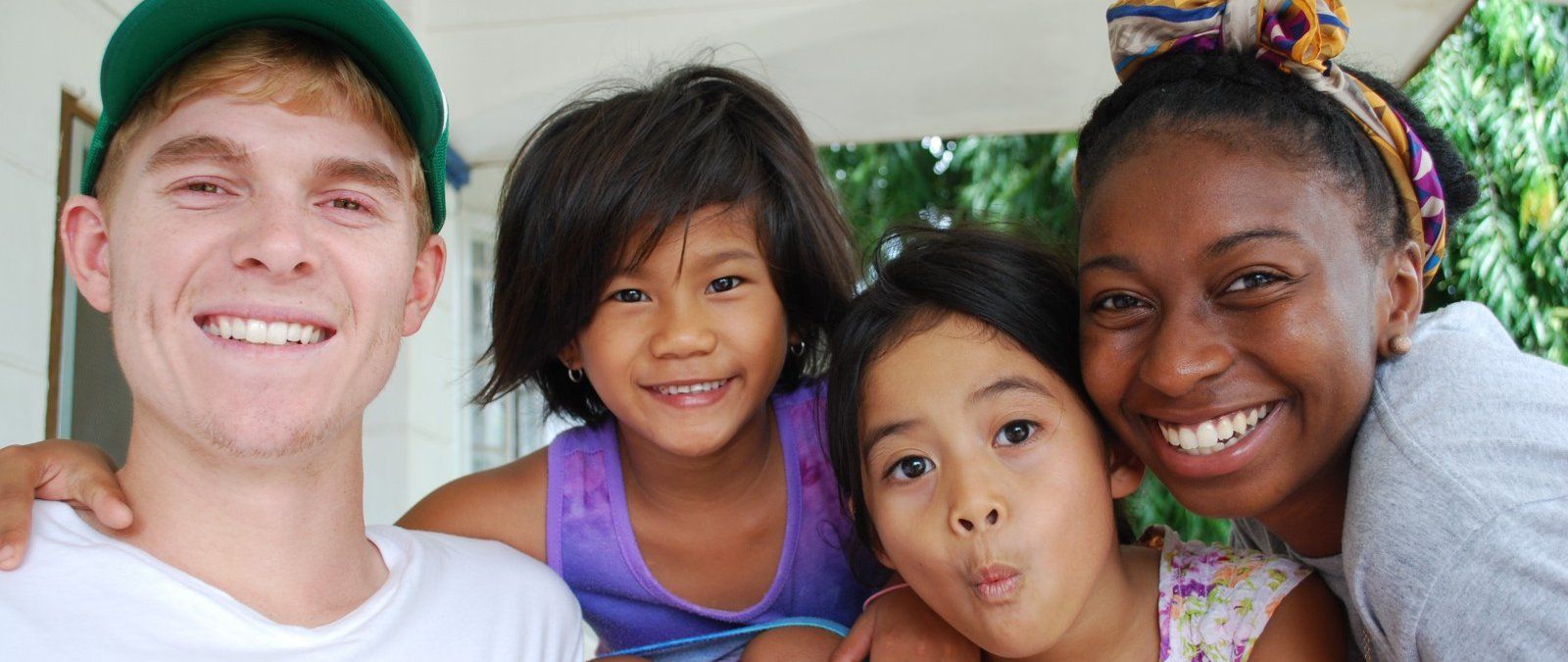 Mitchell and Jordan smile at the camera with Filipino children making funny faces.