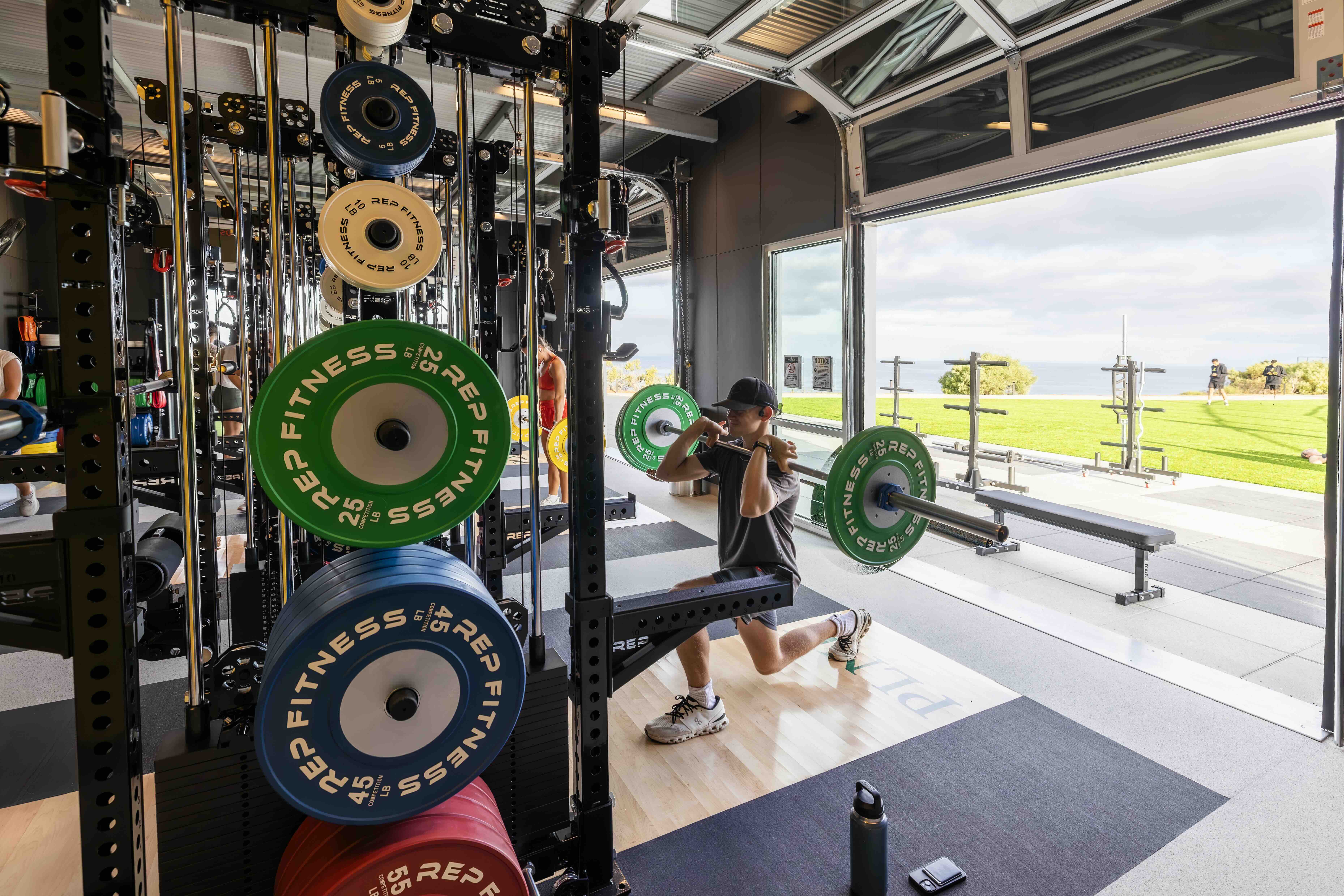Student performing a lunge beside strength training equipment inside the Lawrence Ryan Fitness Pavilion.