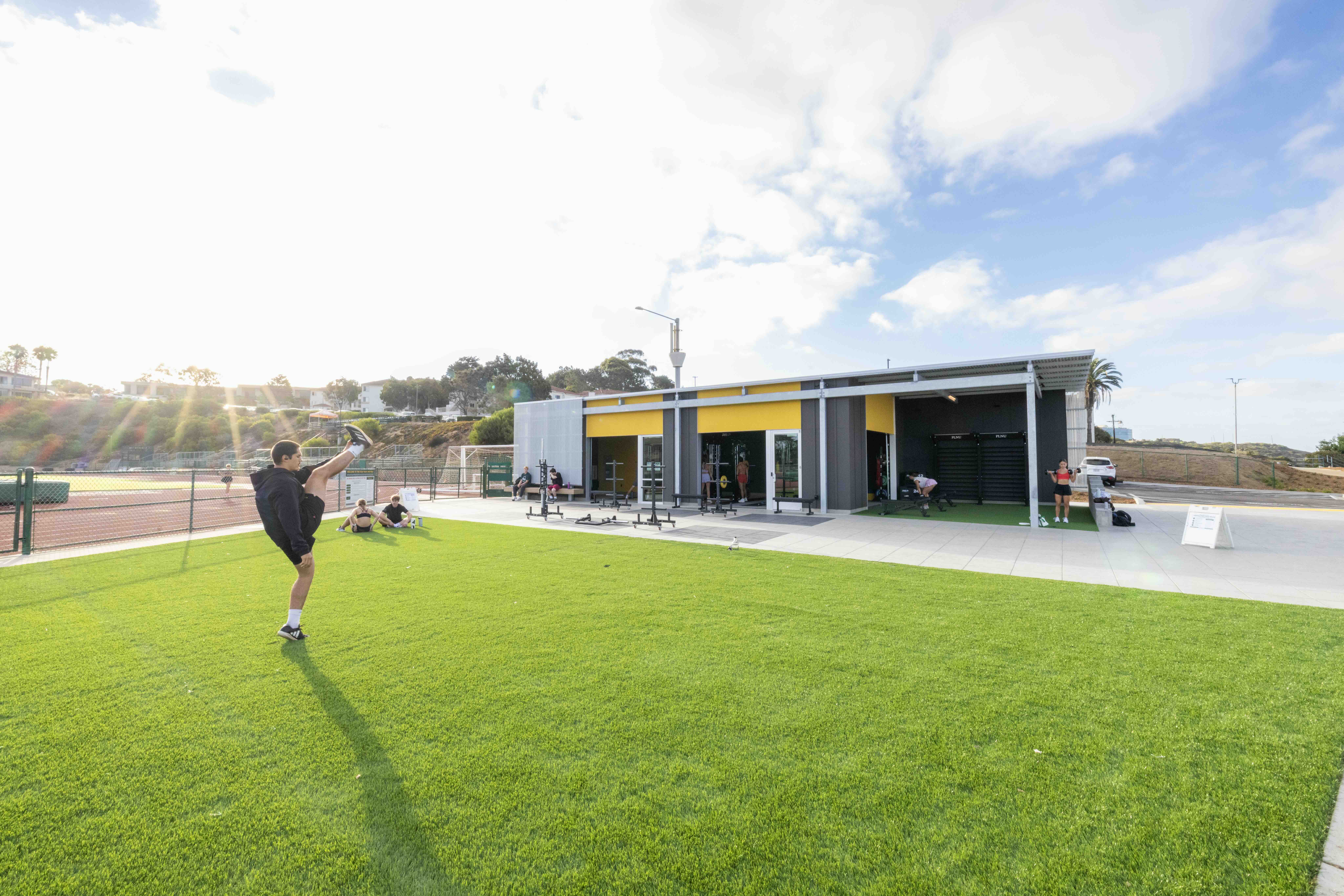 Students exercising and relaxing on the lawn outside the Lawrence Ryan Fitness Pavilion.