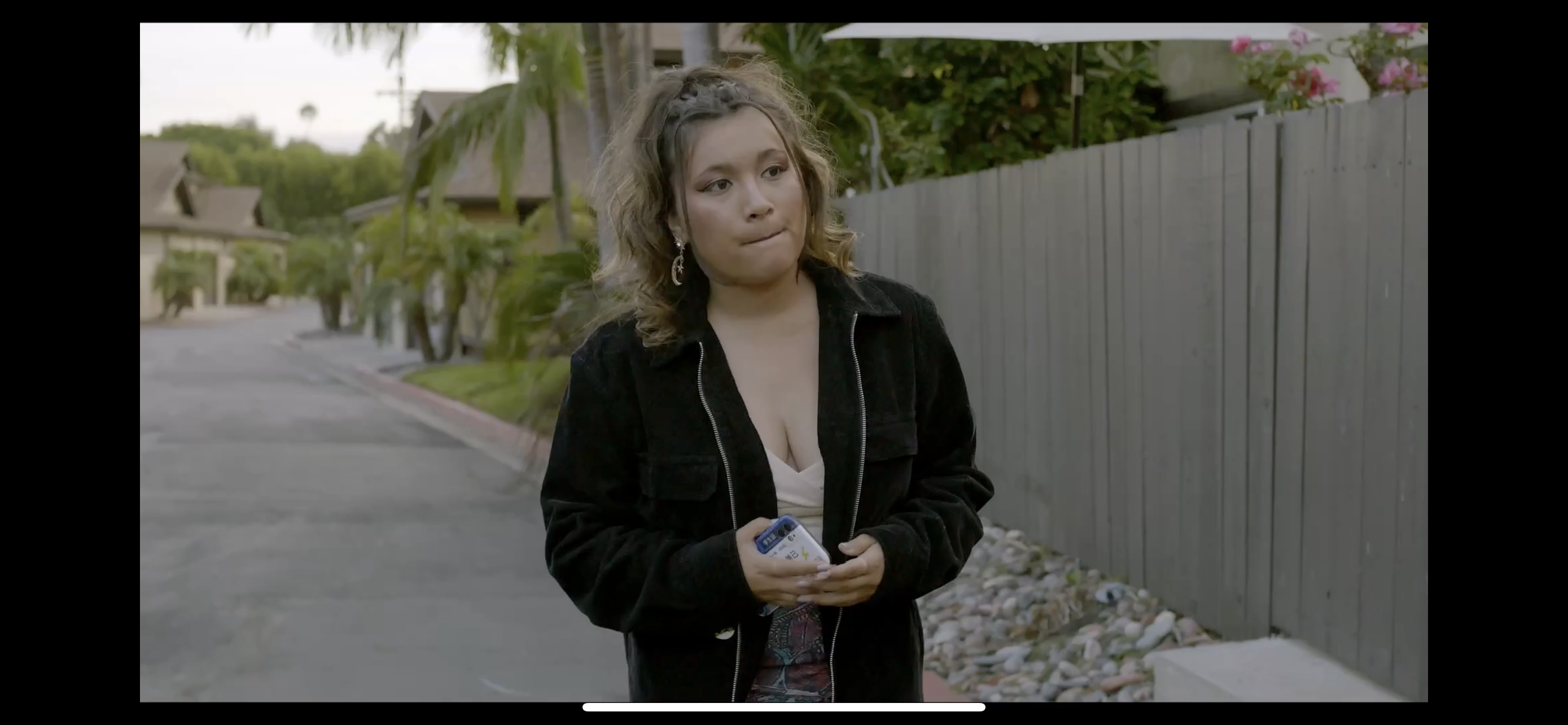 Teenage girl walks down neighborhood street holding cell phone