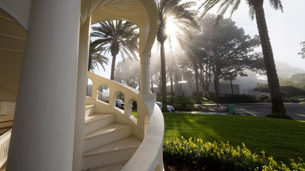 Image of Brown Chapel on a misty day from Mieras Hall steps. Sun is peaking through mist and Brown's Chapel cross can be seen through the light.