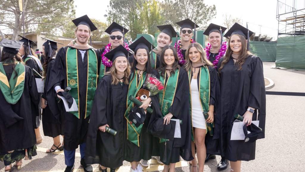 GPS students posing in graduate regalia at the Winter 2022 Commencement.