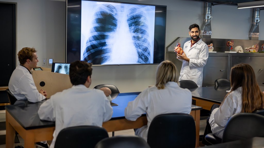 Anatomy professor gives lecture to students with presentation of x-rays in biology lab.