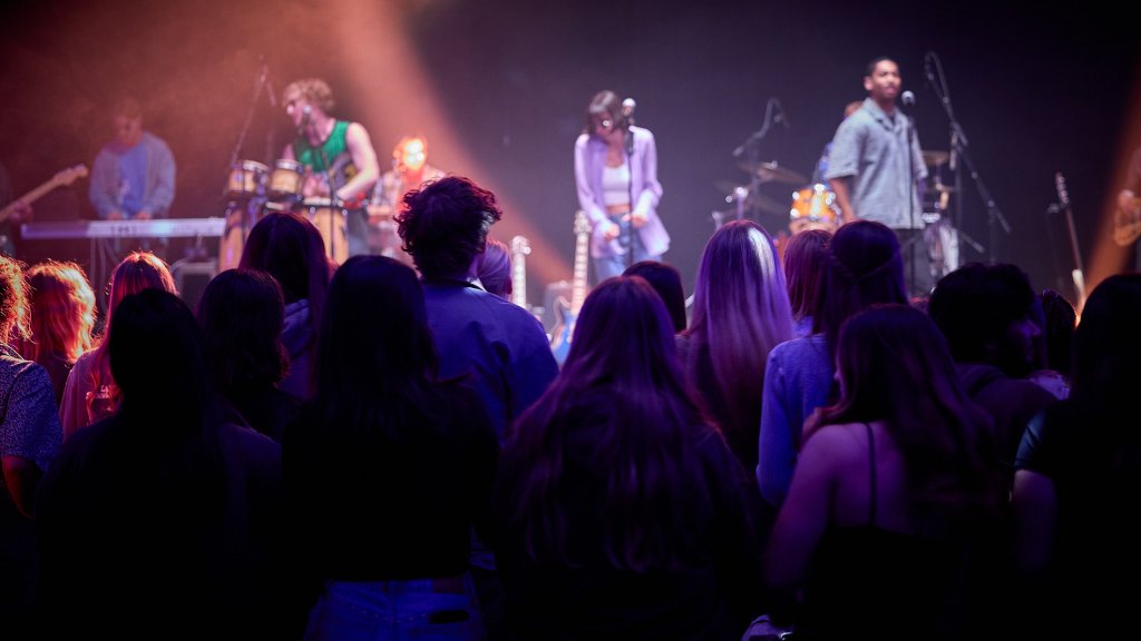 A crowd of PLNU students watch a live band performance under colorful stage lighting in Brown Chapel.