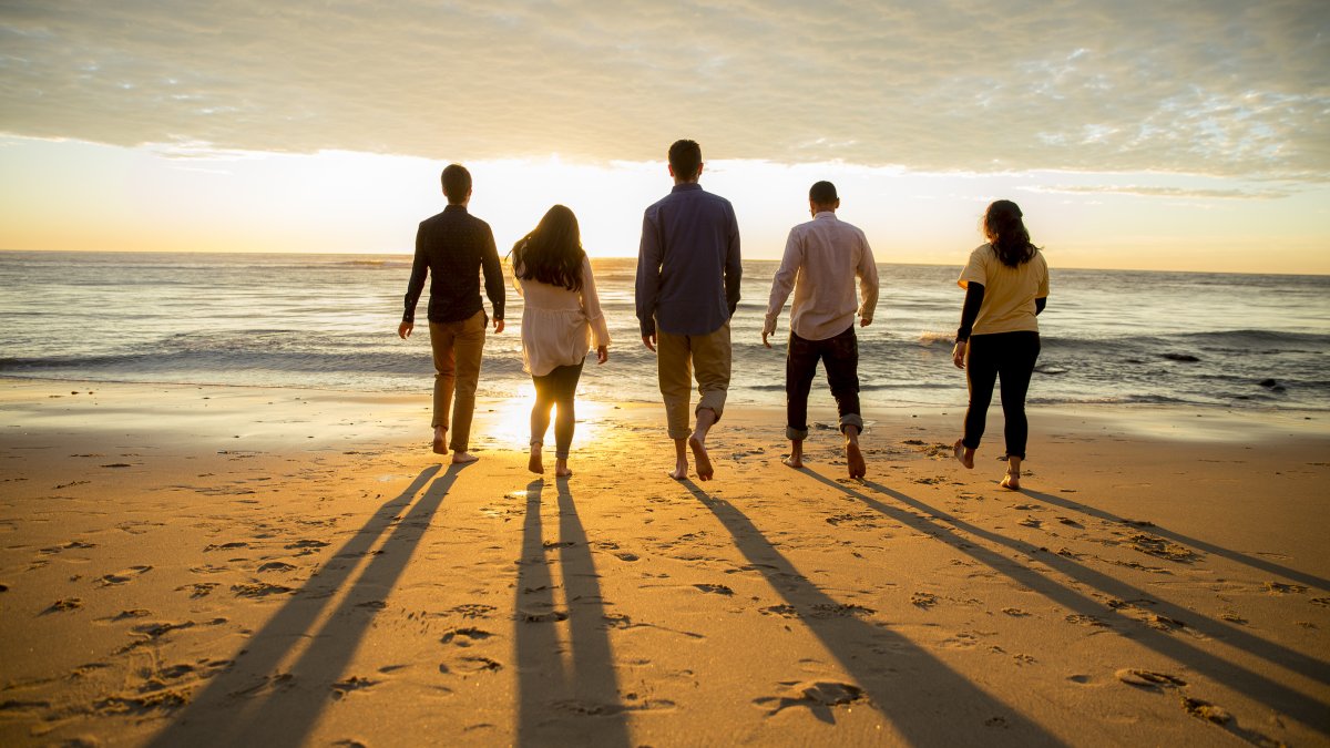 People walk towards the ocean and sunset