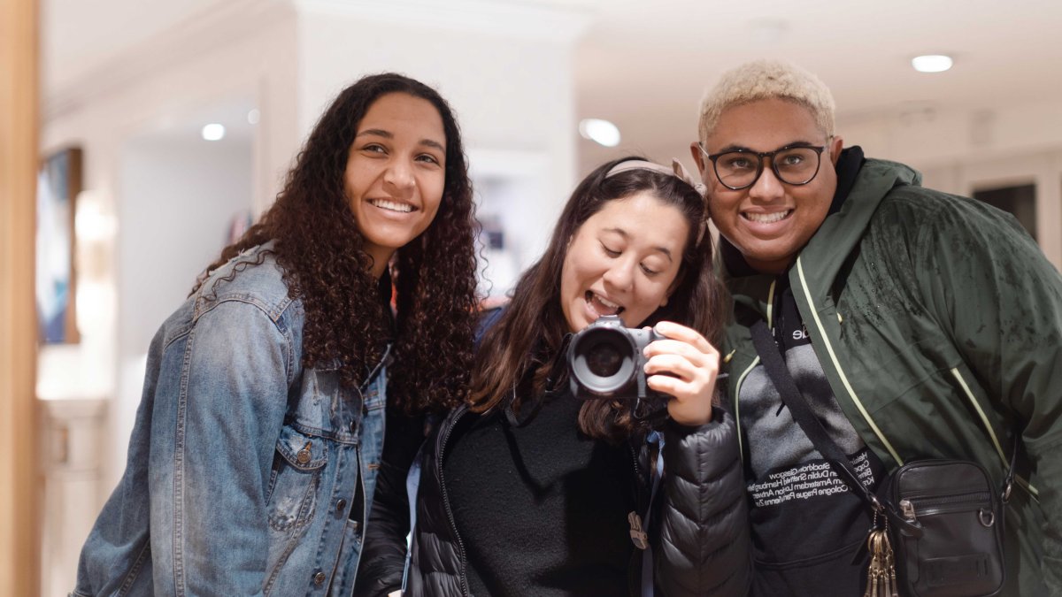 Three PLNU students take a photo with a camera a mirror