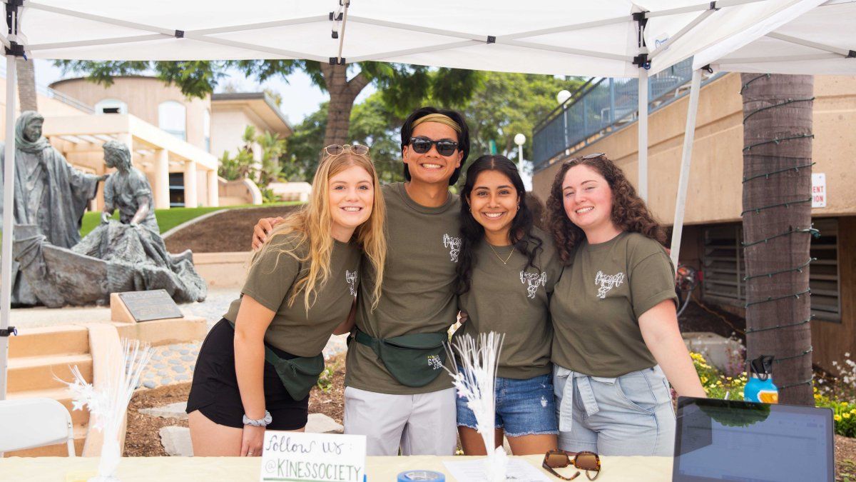 Group of PLNU students smile for a photo at the club fair