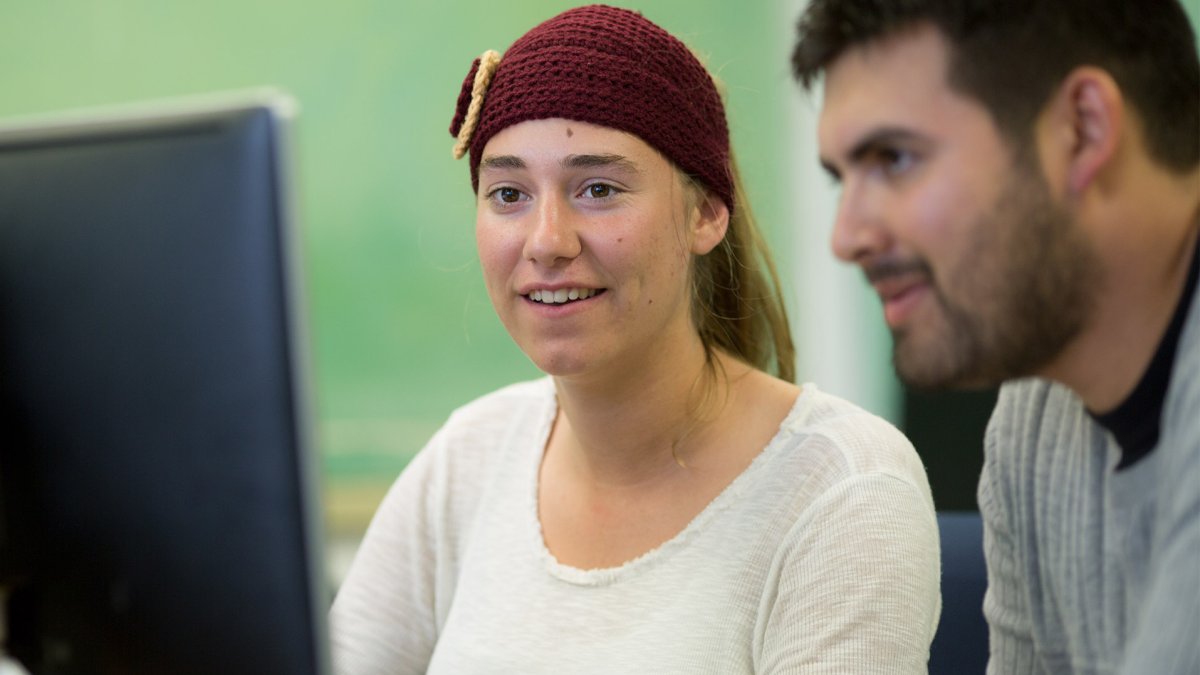 Students sit behind a computer while working on a project.