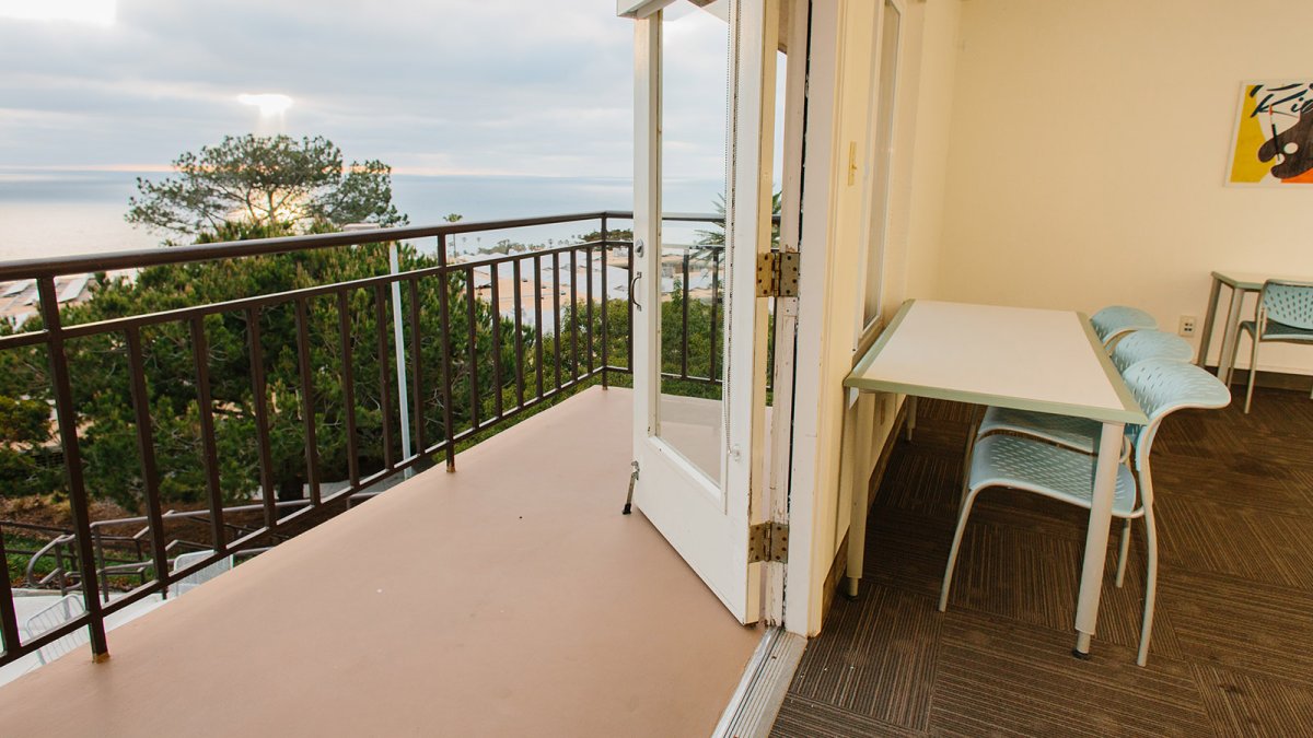 The sun sets over the water past the balcony of Finch Hall's study room.