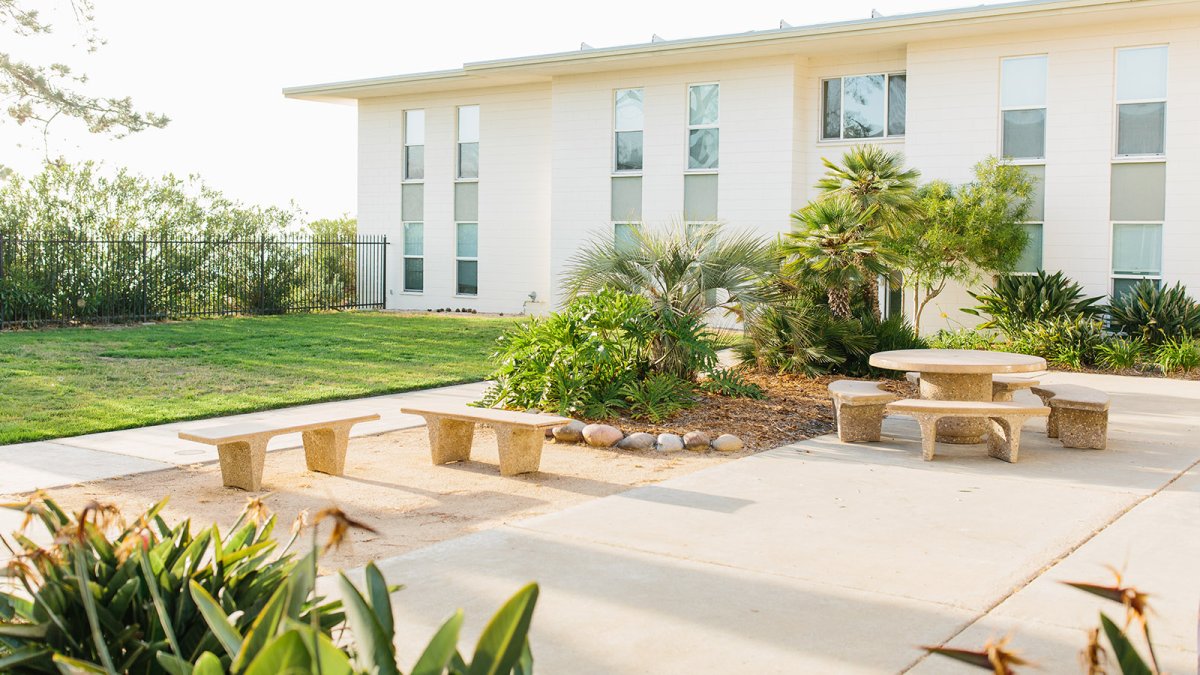 Goodwin Hall's outside area is a warm sunny place to relax with a lawn and park benches all around.