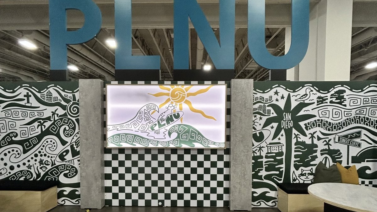 PLNU's vendor set up at the Nazarene Youth Center Conference in 2026 with the university's logo sitting above the set up with Loma graphics along the wall and a seating area for visitors.