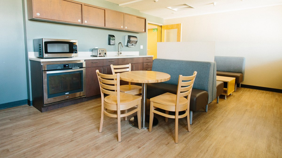 A modern styled community kitchen space with stove, microwave, and plenty of seating.