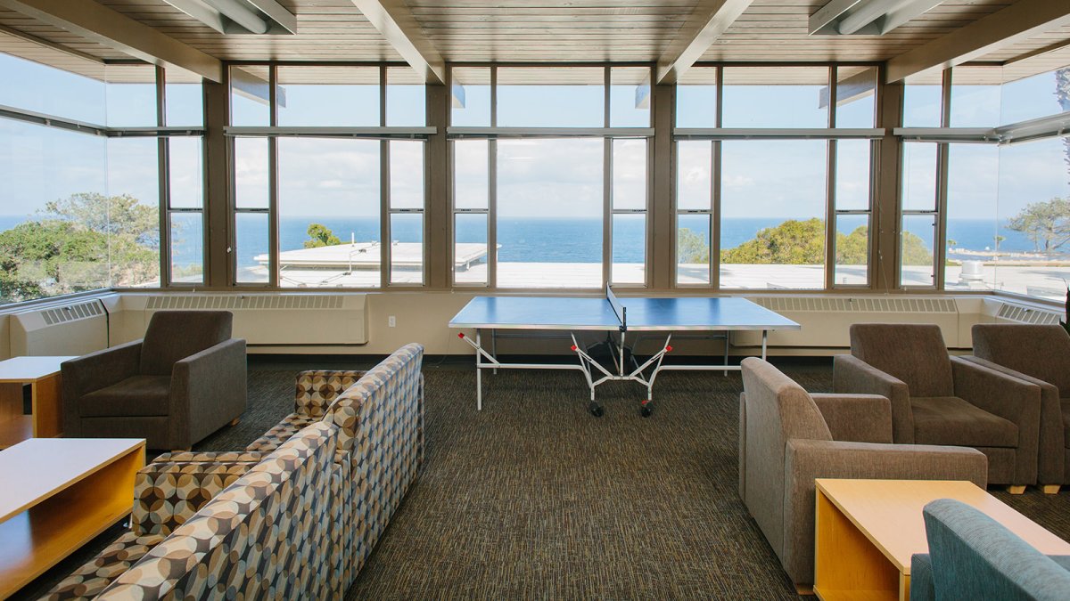 Nease Hall's lounge space has many couches, a ping pong table, and a view of the Pacific Ocean.