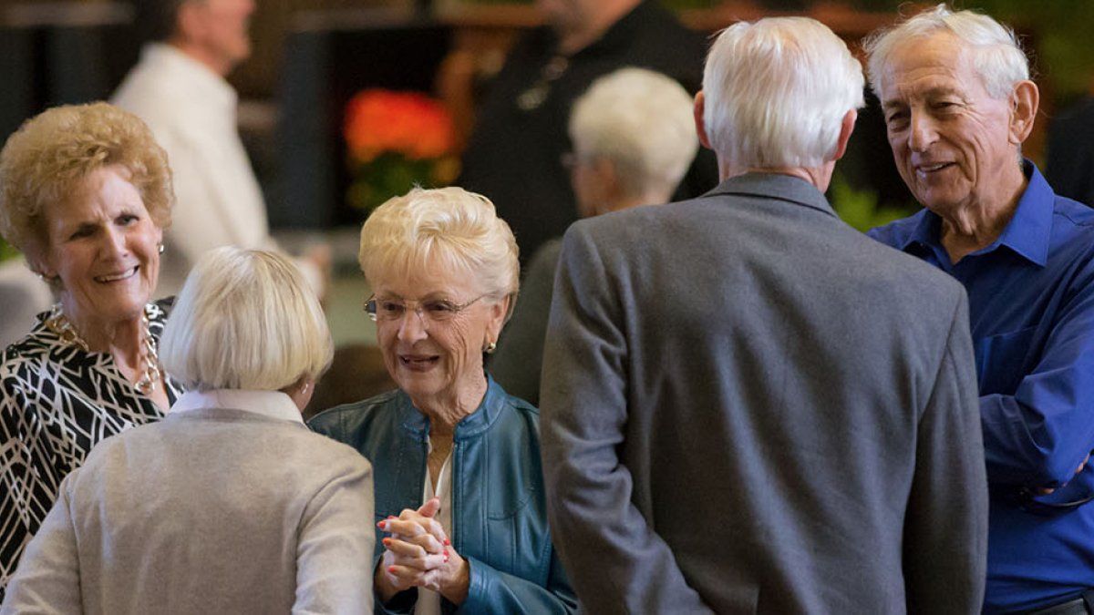 A group of older PLNU alums greet each other and catch up in Brown Chapel during Homecoming