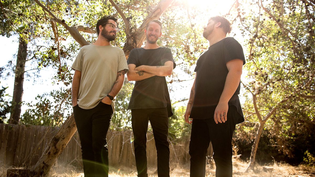 The band Urban Rescue poses for a group photo in a wooded area in the afternoon.