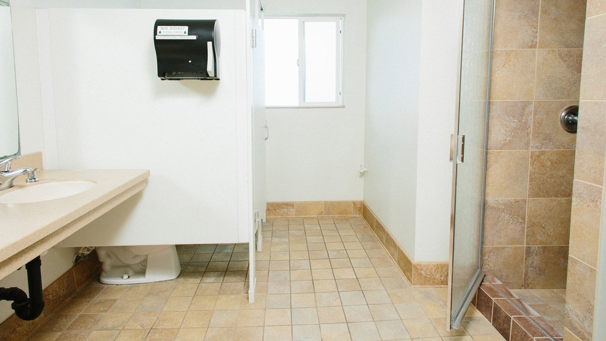 Tan tiled bathroom and individual shower stalls in the Wiley bathrooms.