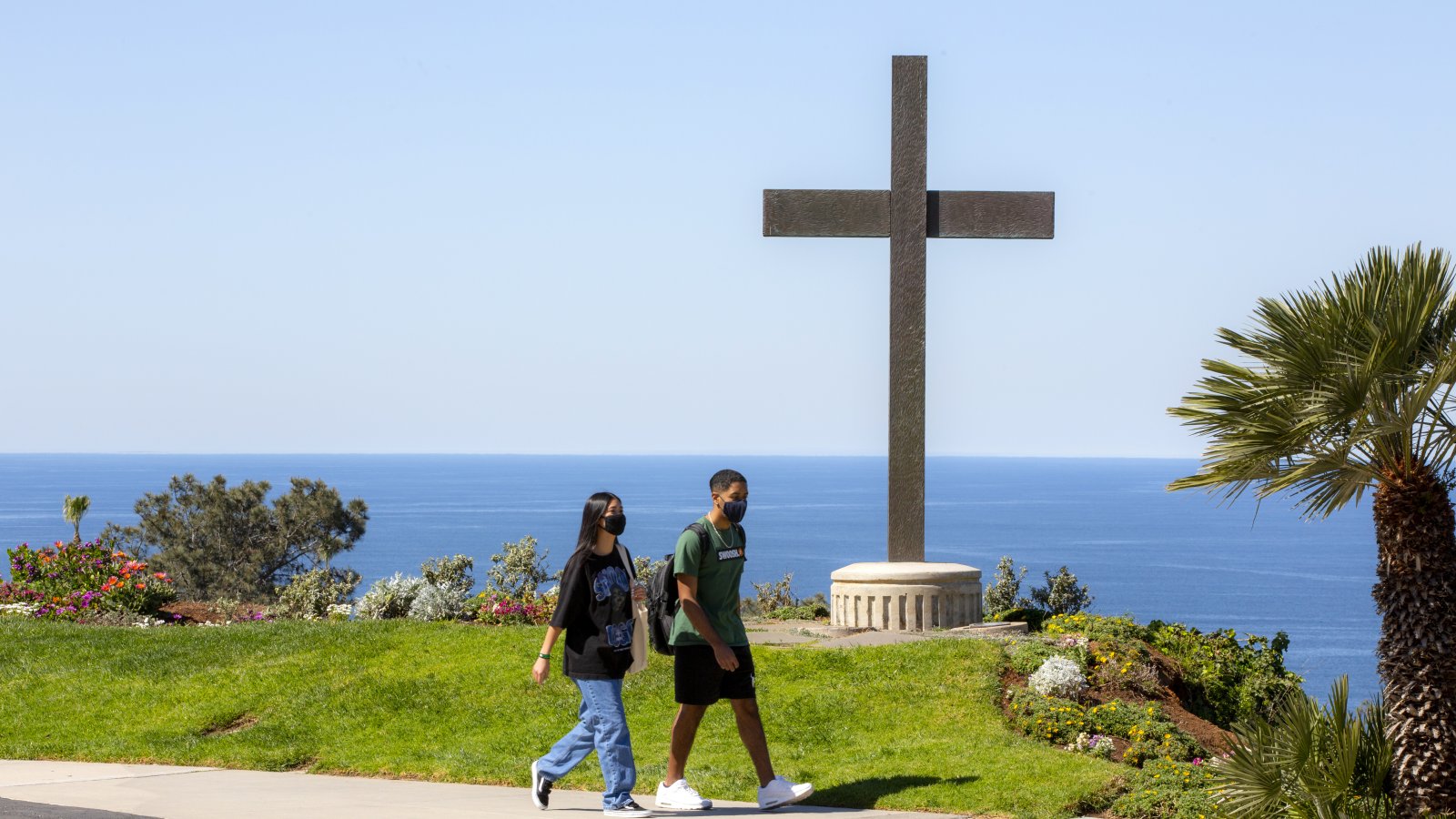 Two students are walking by the cross.