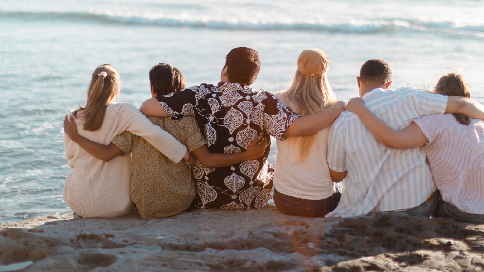 a group of students sit by the beach