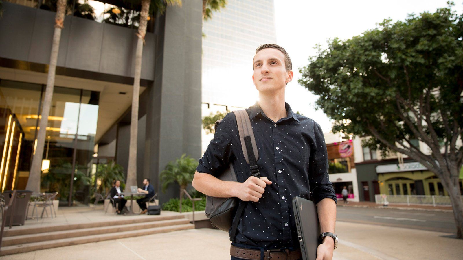 A well-dressed student looks across the street while in downtown San Diego.