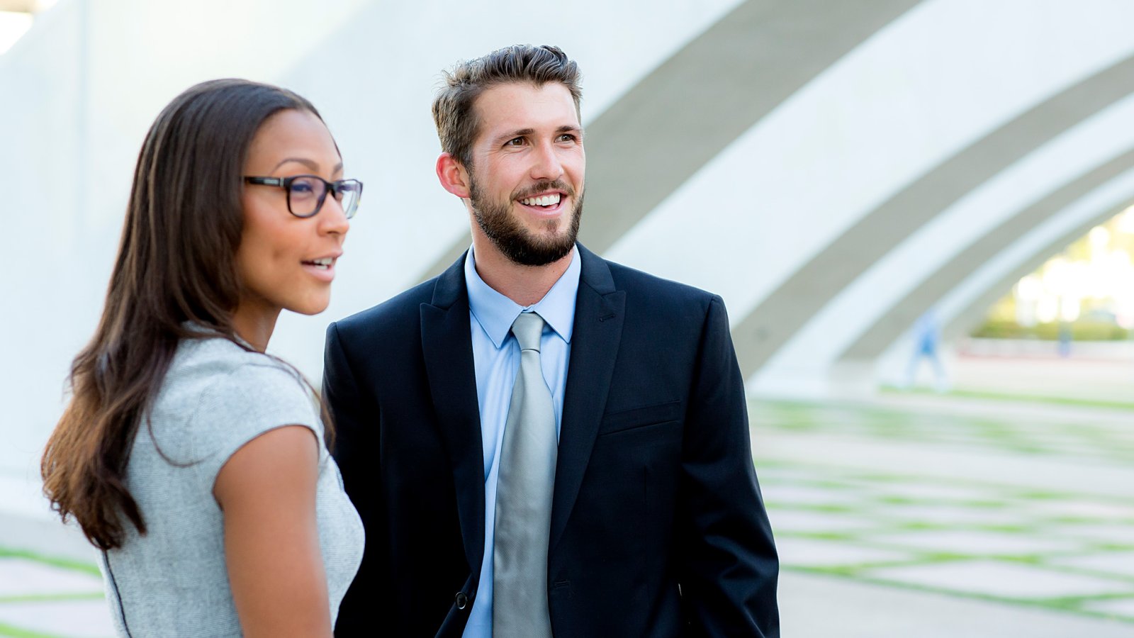 Male and female student look off camera as they meet under structure