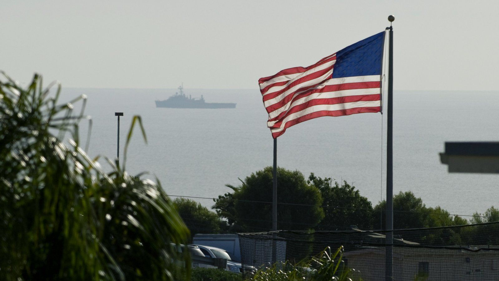 PLNU proudly flies the flag between on campus, while a navy ship maneuvers just off the coast.
