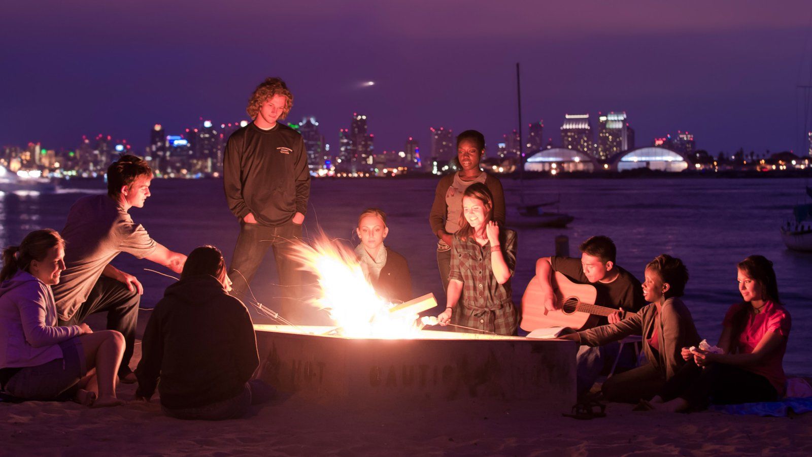 PLNU students gather around a bonfire at Shelter Island.