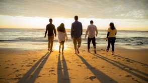 People walk towards the ocean and sunset