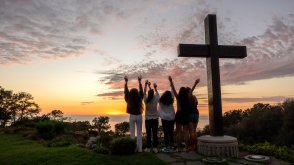 Students raise hands in joy by the PLNU cross