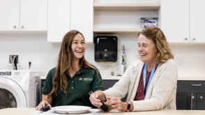 PLNU occupational therapy student and instructor smile while practicing the use of adaptive eating utensils in a clinical learning space.