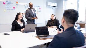 business students in a classroom talking about a project 