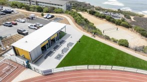 Aerial view of the Lawrence Ryan Fitness Pavilion, athletic track, lawn, and surrounding coastal campus.