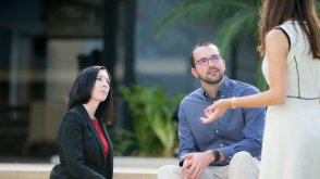 As leaders, we can cripple our organizations if we allow our teams to remain stagnant in their current patterns, pictured is a woman talking to two individuals who are listening intently. 
