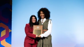 PLNU iWell program director Jessica Matthews stands on the ACLM stage to receive an award.