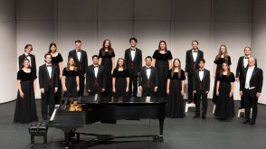 Male and female singers lined up on stage, wearing concert black dresses and tuxedos