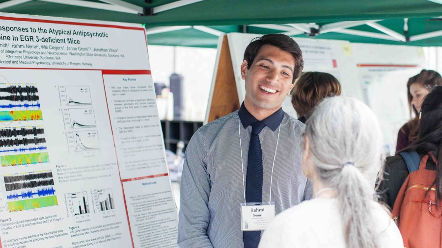 Researcher discusses a neuroscience poster with an attendee during a research conference.