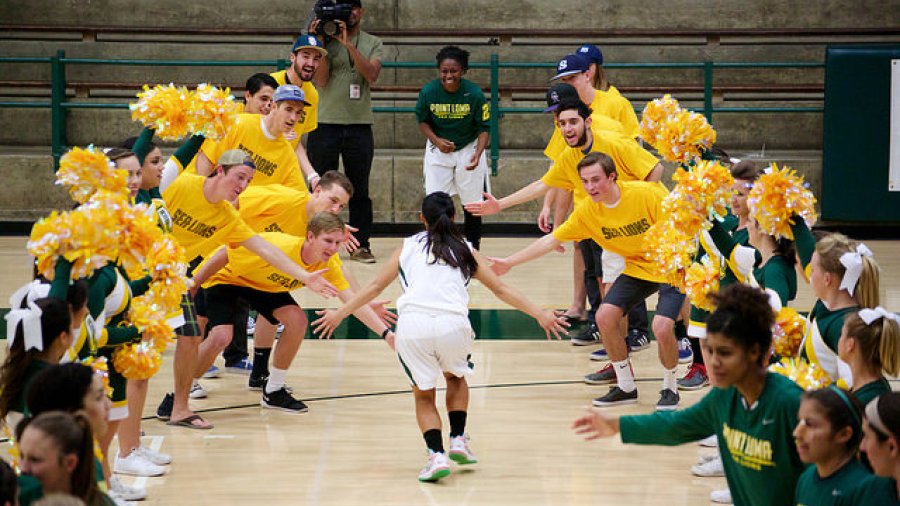 A women's basketball player runs through a tunnel of fans