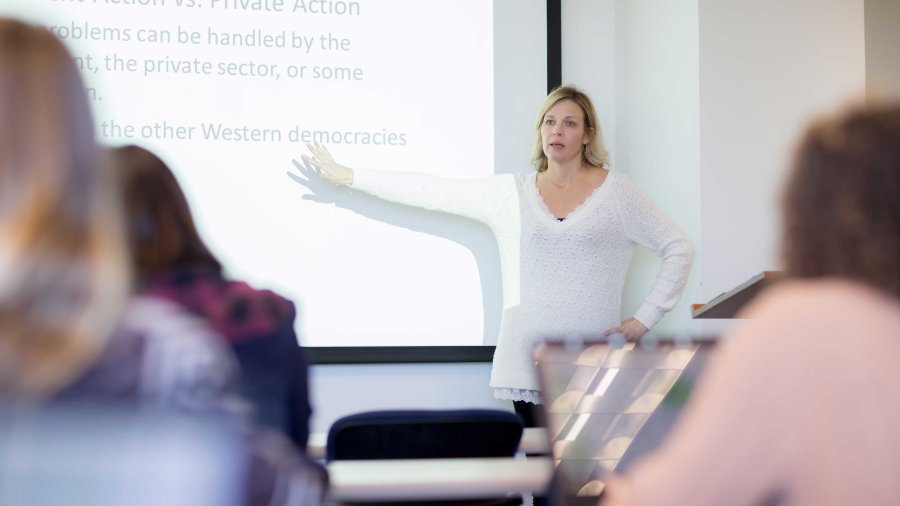 teacher pointing to a screen in a classroom