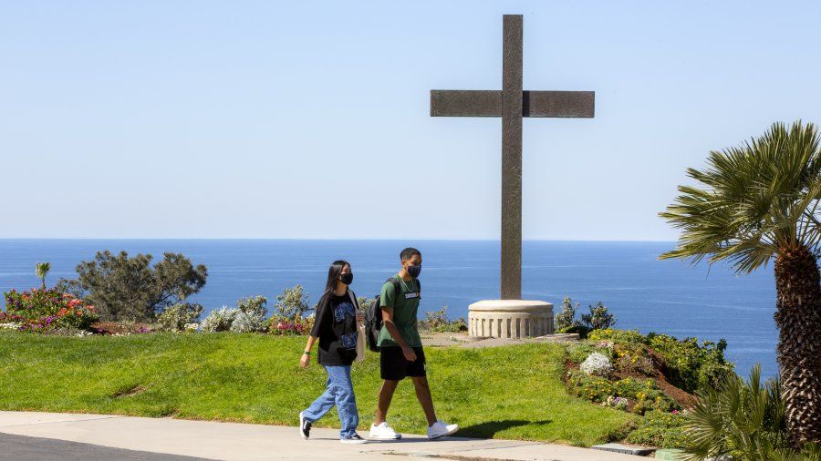Two students are walking by the cross.