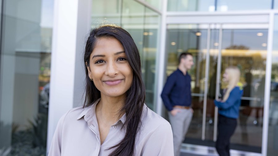 Student looking into the camera while two students are speaking behind her