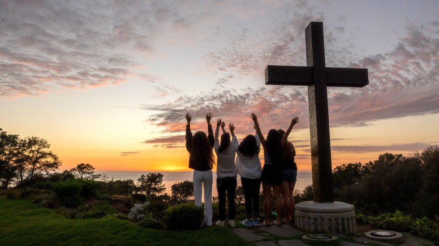 Students raise hands in joy by the PLNU cross