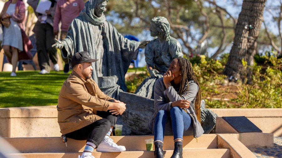 students talking in front of a statue