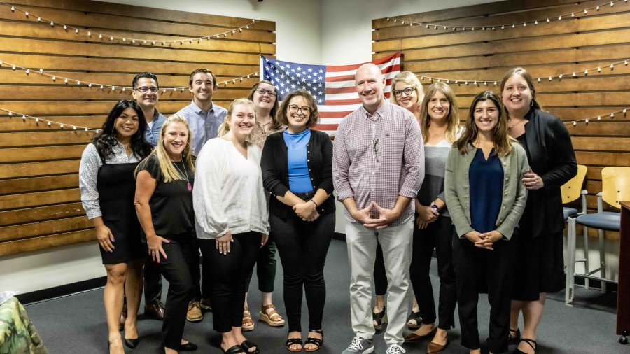 Military veterans pose together for a picture in front of an American flag in Nicholson Commons.