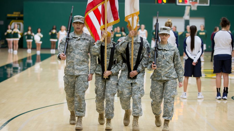 Military students carry the american flag and march during a PLNU basketball game