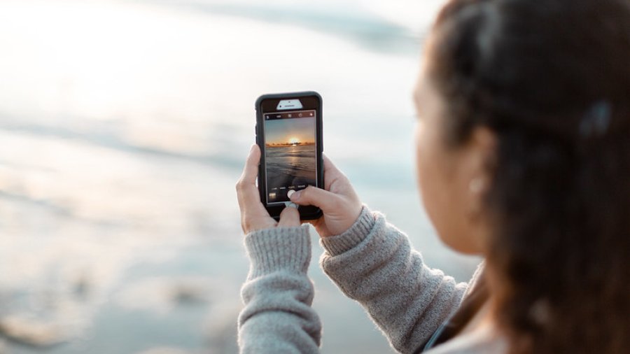 Student with phone takes photo of sunset