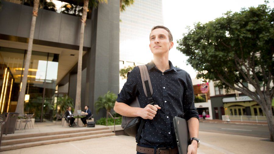 A well-dressed student looks across the street while in downtown San Diego.