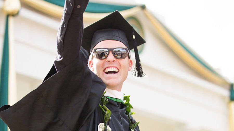 A male student points to the crowd after receiving his diploma
