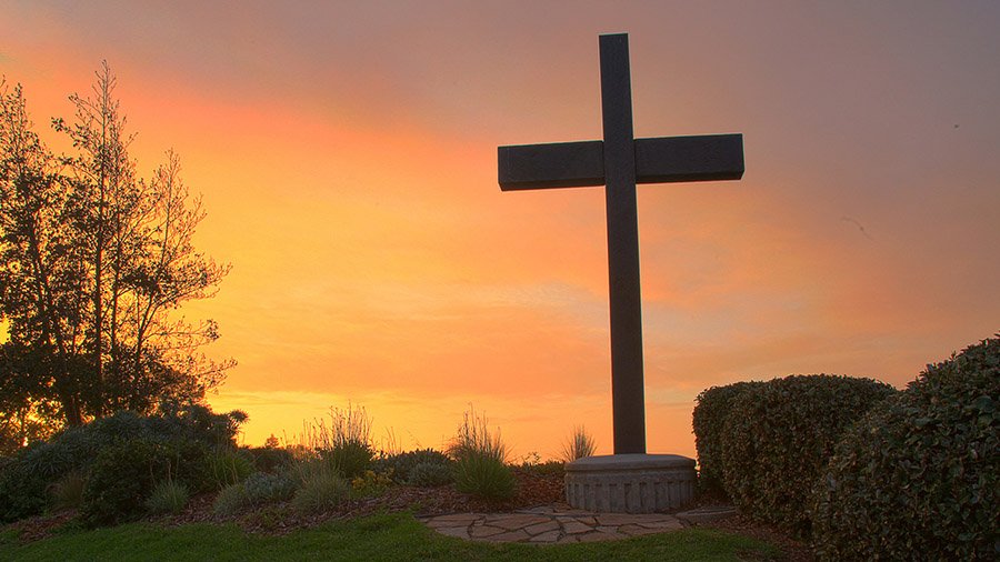 The PLNU campus cross glows during a bright sunset.